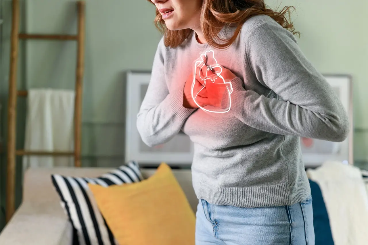 Imagem mostra mulher com dor no peito segurando o coração, representação de risco cardíaco ou problemas de saúde do coração.