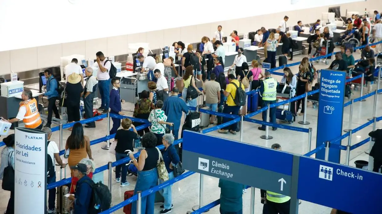 Imagem mostra o aeroporto, onde passageiros aguardam em fila.