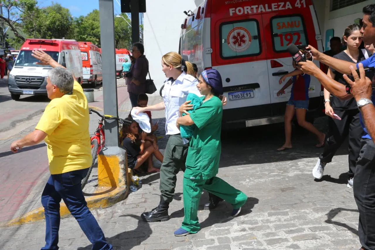 Profissional de saúde carrega bebê nos braços em saída de hospital.