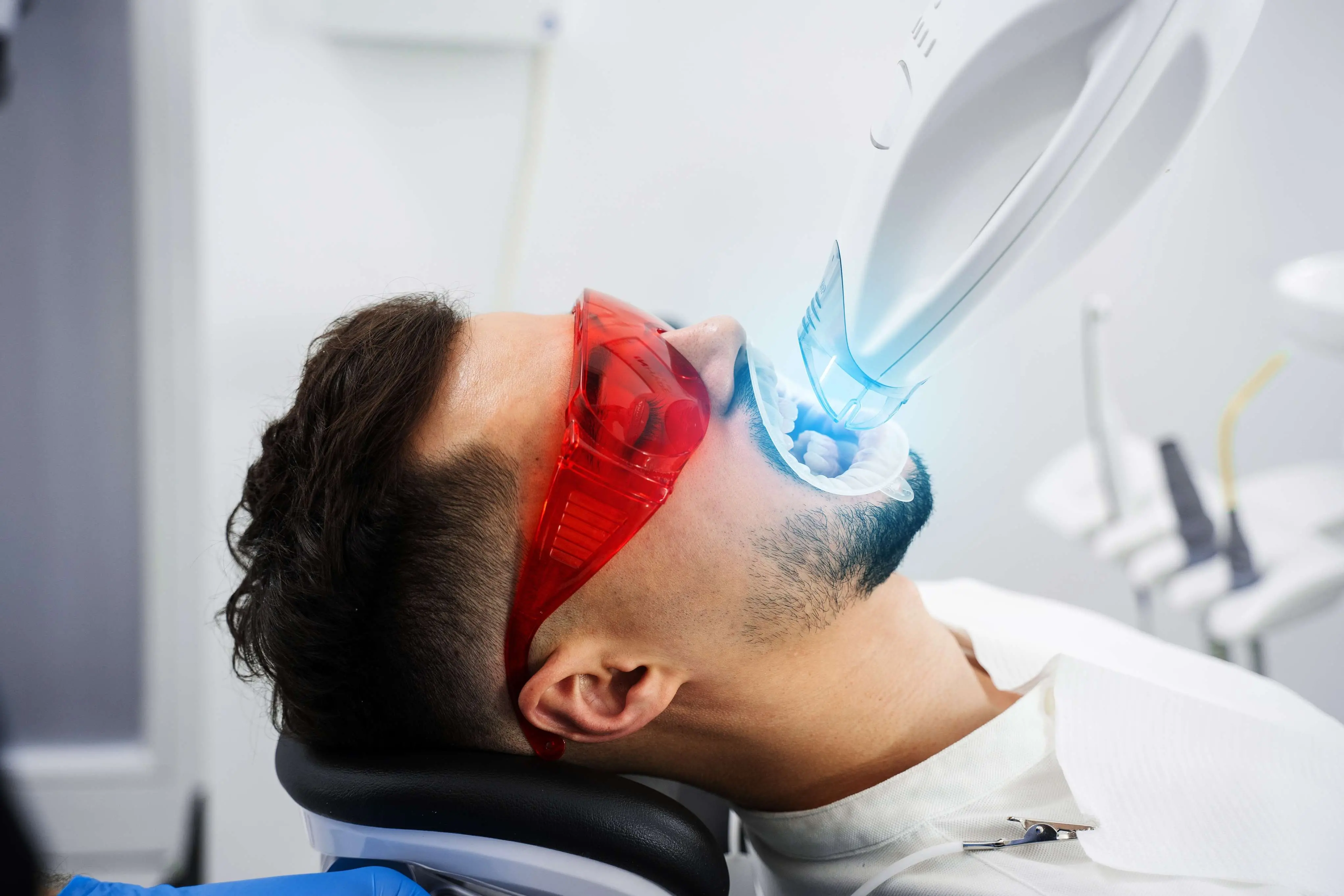 Imagem de um homem realizando clareamento dos dentes.