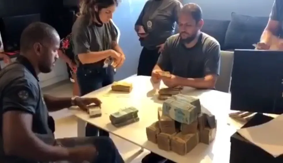 Agentes da Polícia Civil contam cédulas encontradas em cofre na residência de Nego do Borel no Rio de Janeiro