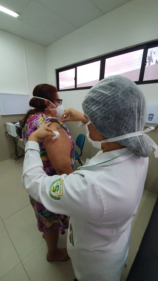 A professora Elaine Carneiro recebendo a primeira dose da vacina Pfizer.