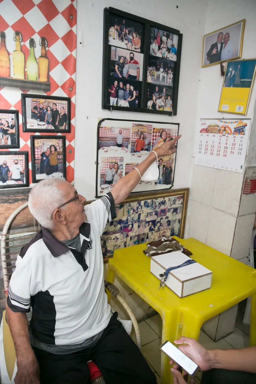 Seu Paraíba aponta para a foto na qual ele está ao lado do ex-presidente Lula: orgulho
