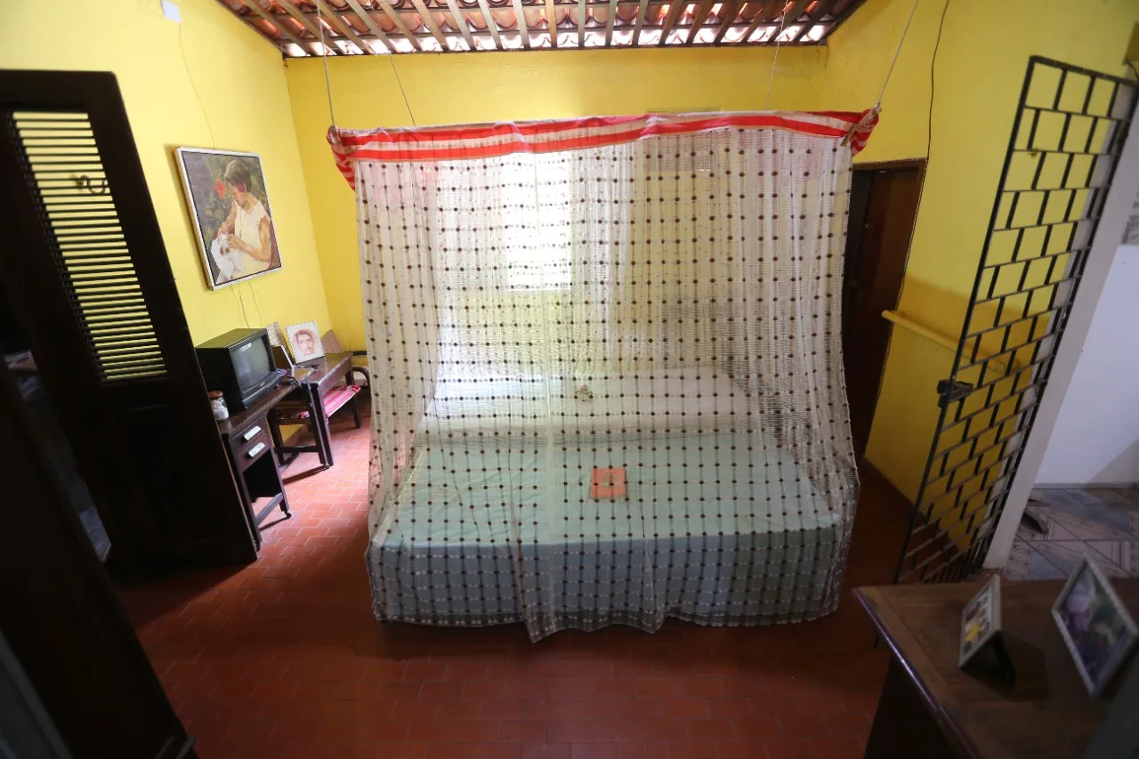 No quarto do casal, além da cama, estão porta-retratos, uma televisão, um telefone e outras minúcias