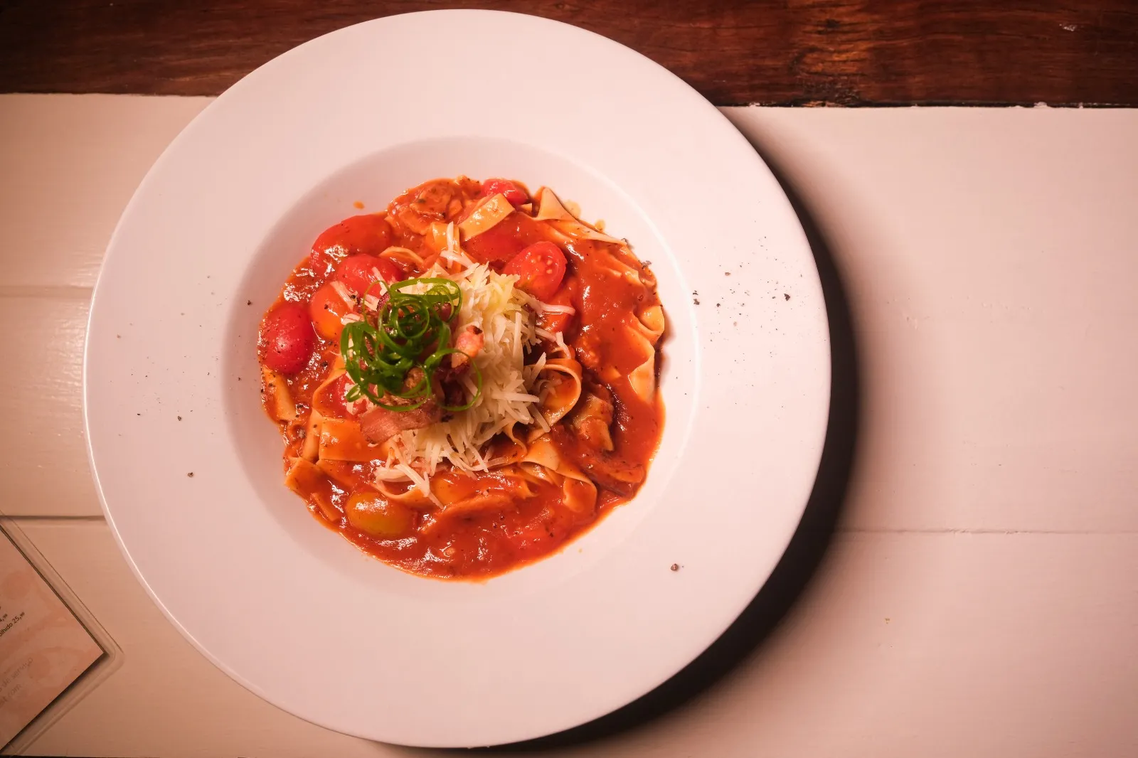 Pasta Amatriciana é servida com molho à base de bacon e tomate, bacon crocante e parmesão em cima, com cebolinha