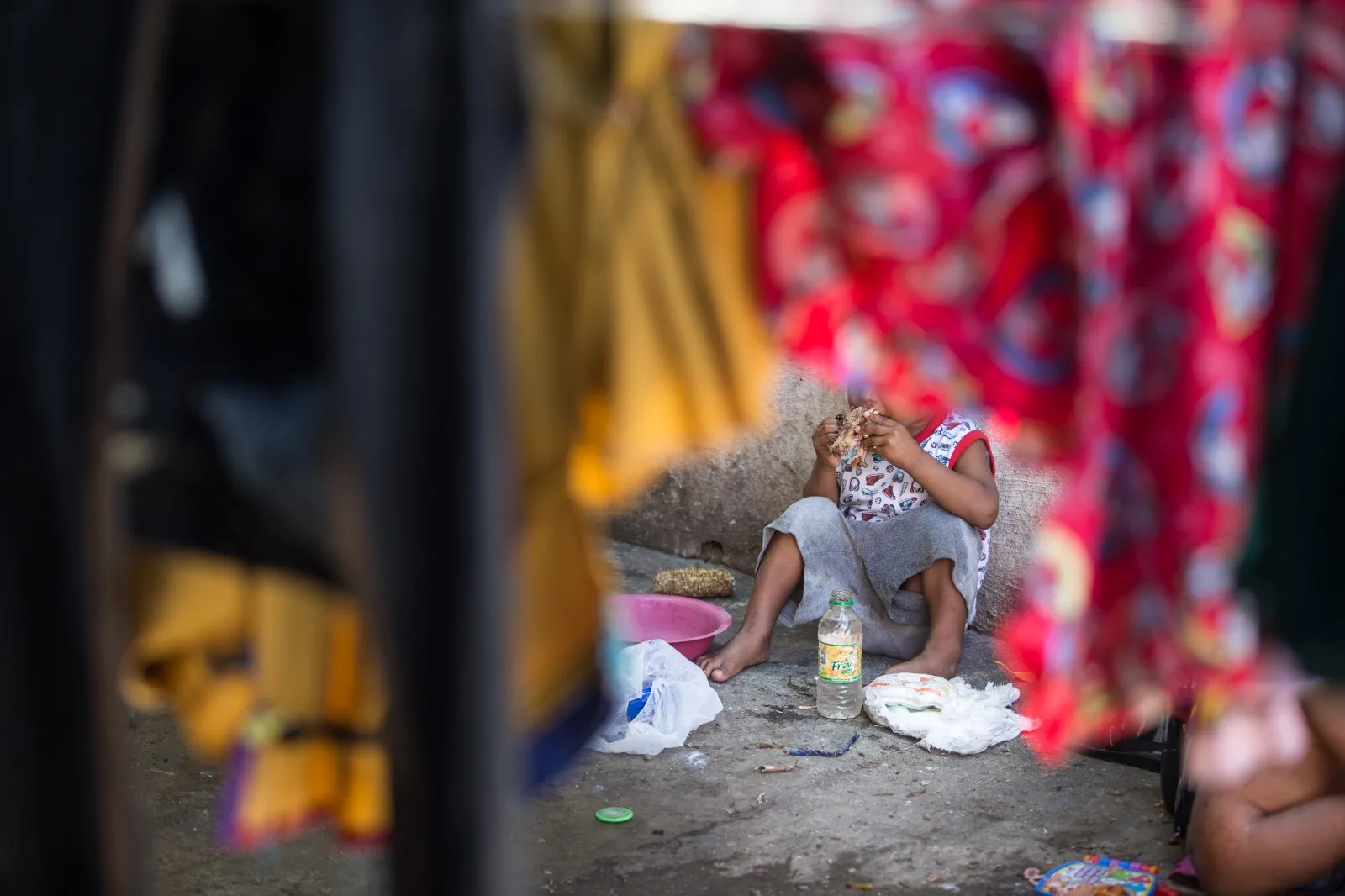 Os refugiados fazem as refeições no chão, em meio ao esgoto e ao lixo