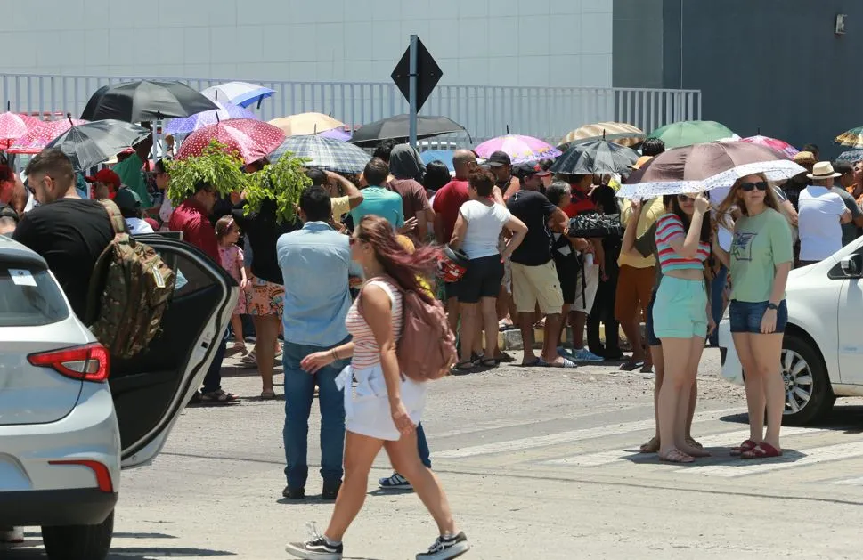 Visitantes contam com o auxílio de guarda-chuvas para enfrentar o sol durante espera