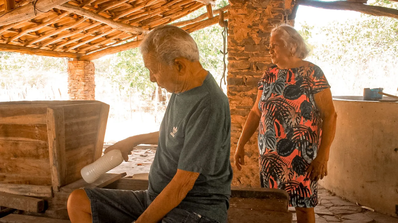 O casal junto ao fogão de lenha da casa no interior