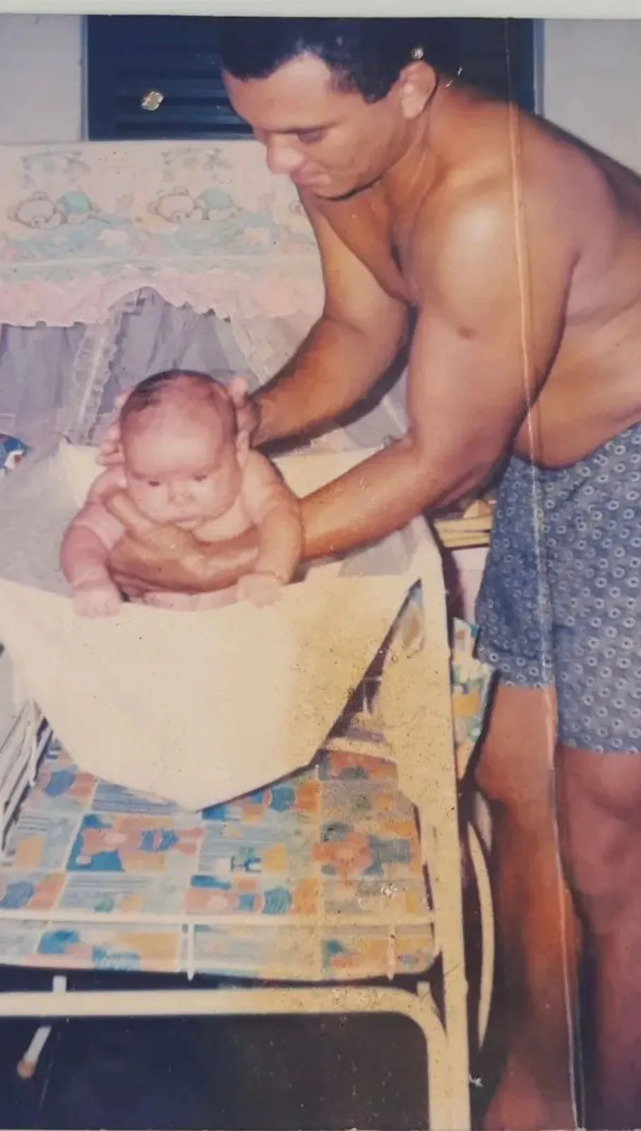 O pai dando banho na filha mais velha nos primeiros meses dela de vida