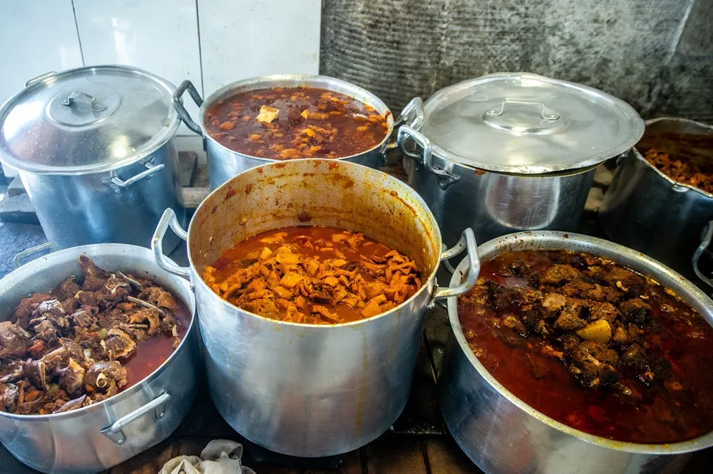 Panelões no fogão à lenha e mais 14 panelas de pressão na cozinha interna integram trabalho no Iran da Panelada