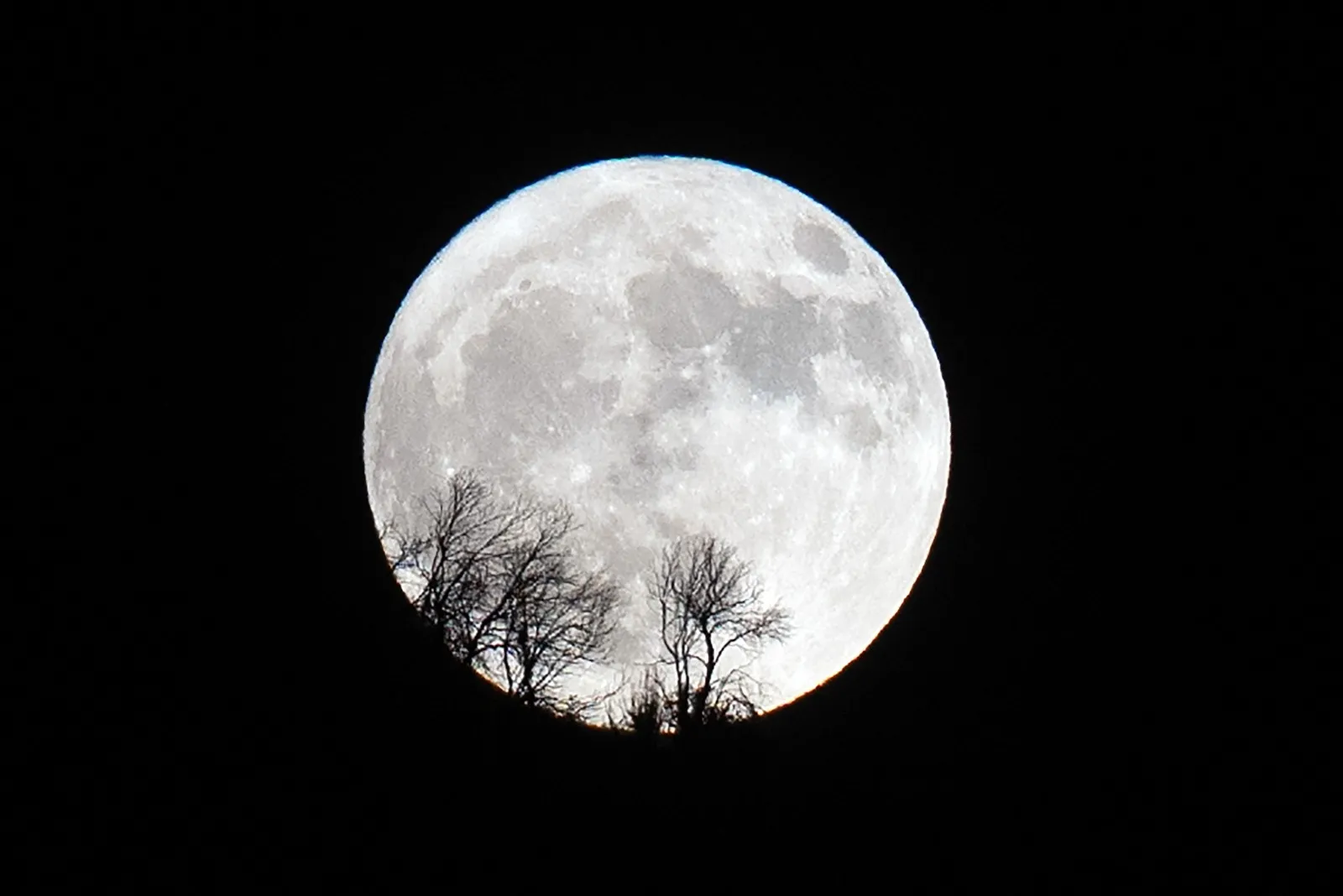 Uma superlua cheia surge atrás de uma montanha na vila de Dodecametro, na região de Arcádia, na Grécia.
