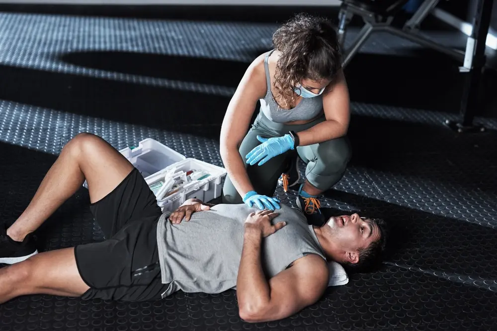 foto de homem passando mal e sendo atendido por funcionária em academia para ilustrar matéria sobre morte súbita durante o treino.
