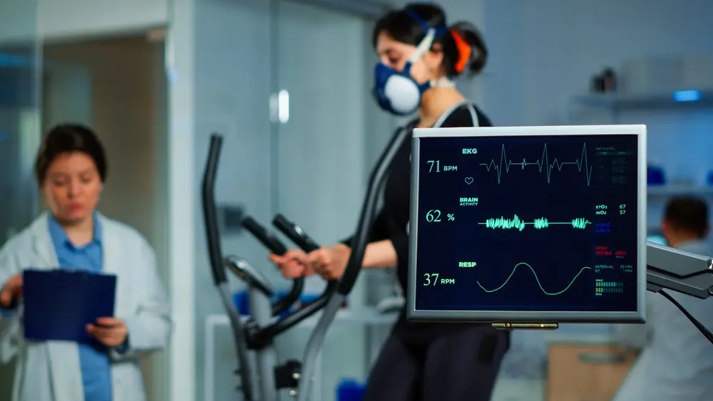 Pessoa em teste ergoespirométrico e monitor cardíaco avaliando o teste.